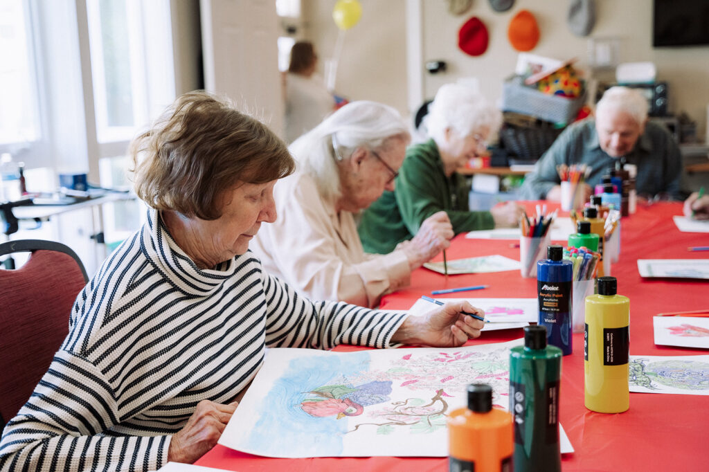 Residents in the art room painting at the table